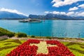 Flowerbed of the Swiss flag with boat cruise on the Thun lake and Alps mountains, Oberhofen, Switzerland. Swiss flag made of Royalty Free Stock Photo