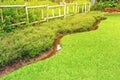 Flowerbeds with green grass in the garden, fence made of bamboo, Garden with a Freshly Mowed Lawn, Flowers bed with green grass. Royalty Free Stock Photo