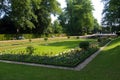 Flowerbeds in park with fountain in background.