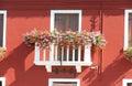 flowered balcony with a window in the house and many flower pots