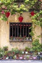 Flowerpots with flowers, yellow wall and window with red chinese lanterns in Hoi An old town, Vietnam Royalty Free Stock Photo