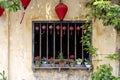 Flowerpots with flowers, yellow wall and window with red chinese lanterns in Hoi An old town, Vietnam Royalty Free Stock Photo