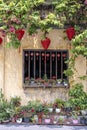 Flowerpots with flowers, yellow wall and window with red chinese lanterns in Hoi An old town, Vietnam Royalty Free Stock Photo