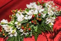 Bouquet of white lilies with spots and red fruits on red cloth. Lilium `Stargazer. Royalty Free Stock Photo