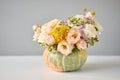 Flowers arrangement in pumpkin on the white table. Fresh cut flowers for decoration home. European floral shop. Delivery