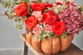 Flowers arrangement in pumpkin on wooden table. Fresh cut flowers for decoration home. European floral shop. Delivery