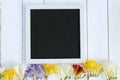 Flowers with blank black chalkboard picture frame on a light wooden background. romantic picture. Royalty Free Stock Photo