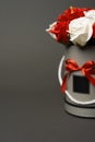 Flowers in bloom: A bouquet of red and white roses in a gray round box on a gray background.