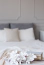 Flowers and books in front of comfortable bed in classy bedroom interior