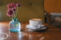 Flowers in botle of blue color on tabletop and cup of coffee