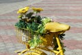 A yellow decorative bicycle with flowers stands in the parking lot on a summer day. Royalty Free Stock Photo