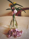 A flowers bouquet in a vase on a table with withered rose and fallen petals