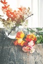 Flowers. Bright tulips lie on a wooden background. a glass vase with small white flowers in the background. Romantic still life Royalty Free Stock Photo