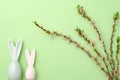 Flowers composition. Blossoming branch, eggs and ceramic rabbits on green pastel background. Spring, easter concept. Flat lay, top Royalty Free Stock Photo
