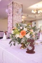 Flowers composition with orange and beige flowers and number three on the table for guests on wedding hall. Wedding table number. Royalty Free Stock Photo