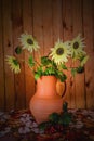 Flowers of a decorative sunflower in a clay jug and a branch of red viburnum against a wall of pine boards at the end of summer.