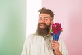 Flowers delivery concept. Man with beard cheerful face holds bouquet fresh flowers. Hipster with beard ready holiday