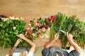 Florist and assistant in flower shop delivery make rose bouquet, table top view