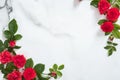 Flowers frame with roses buds and green leaves on marble background. Minimal flat lay style floral composition, top view, banner