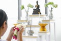 Flowers garland in hands of asian buddhist woman worship to buddha statue at home