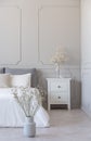 Flowers in grey vase on the floor of simple bedroom