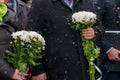 Flowers in hands at a solemn laying ceremony or a memorial day of mourning in bad winter weather under snow Royalty Free Stock Photo