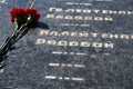 Flowers on the memorial to fallen soldiers, red carnations on black marble, Russian text of soldiers military rank - sergeant,