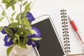 Flowers and mobile with notebook on table white