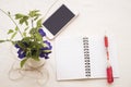 Flowers and mobile with notebook on table white