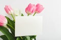 Flowers mock up congratulation. Congratulations card in bouquet of pink tulips on white background. White blank card with space Royalty Free Stock Photo