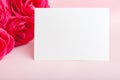 Flowers mockup congratulation. Wedding invitation card in bouquet of pink red roses on pink background. White blank card with Royalty Free Stock Photo