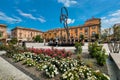 Flowers and modern fountain with big sculpture on town square in Alba, Italy