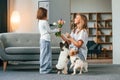 With flowers. Mother with her daughter and with two cute dogs is in domestic room Royalty Free Stock Photo