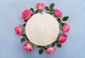 Flowers pink roses with white circle paper card note with space for text on a blue background. Top view, flat lay Royalty Free Stock Photo