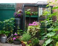 Flowers and plants planting in a urban garden with a small greenhouse full with new own grown vegetables. Nice green natural garde Royalty Free Stock Photo