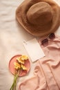 Flowers on the plate with hat, galsses and card on the light background