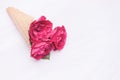 Flowers red roses in a waffle cone on white wooden background. Flat lay, top view, floral background, toned Royalty Free Stock Photo