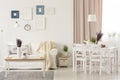 Flowers on table in white living room interior with pink drapes and posters above sofa. Real photo Royalty Free Stock Photo