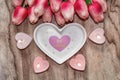 Flowers tulips, a heart-shaped plate and a heart-shaped candle. Festive background to the St. Valentine`s Day in pink colors. Royalty Free Stock Photo