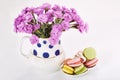 Flowers in vase with macaroons on saucer. Carnations and sweets. Royalty Free Stock Photo