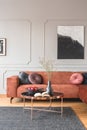 Flowers in vase and red fruits in bowl on wooden coffee table in elegant living room interior