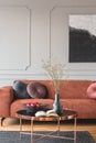 Flowers in vase and red fruits in bowl on wooden coffee table in elegant living room interior