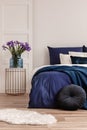 Flowers in vase on stylish nightstand in bright bedroom interior Royalty Free Stock Photo