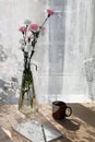 Flowers in a vase on a sunny window in a rustic house on a wooden table