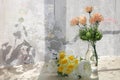 Flowers in a vase on a sunny window in a rustic house on a wooden table