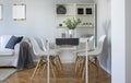 Flowers on white dining table with four trendy chairs in stylish living room