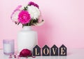 Flowers in a vase and word Love arranged from wooden letters near the pink wall Royalty Free Stock Photo