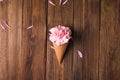 Flowers in a waffle cone. Pink carnations. Flowers on a wooden background.