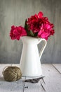 Flowers in white enamel pitcher on a white wooden surface Royalty Free Stock Photo