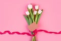 Flowers are white tulips, flatlay. A beautiful bouquet tied with a red ribbon and an envelope on pink background. Royalty Free Stock Photo